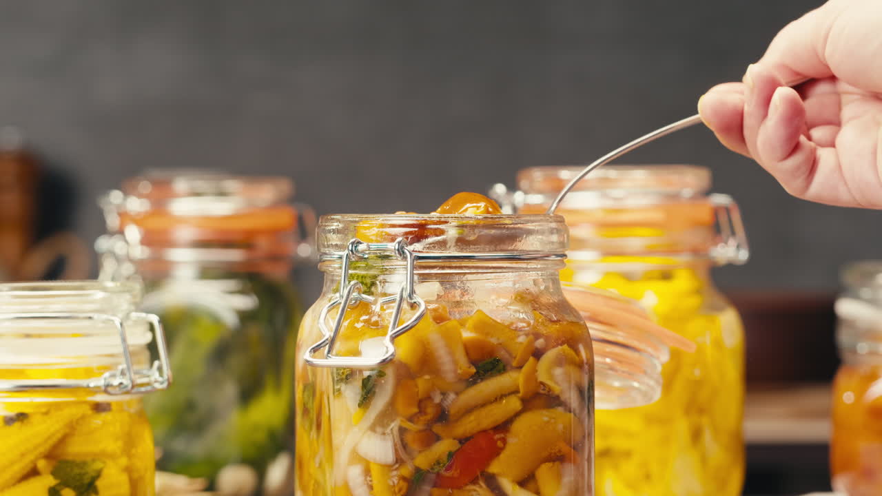 Fermented food in glass cans on table close-up. Preservation of vegetables in glass jars. Fermentation preserved mini corns, kimchi, cucumbers, mushrooms with spices.