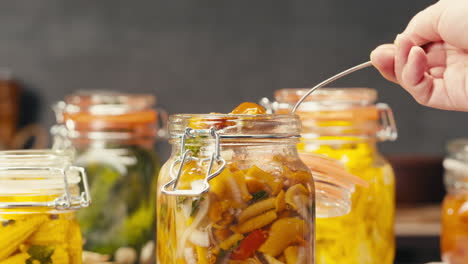 fermented food in glass cans on table close-up. preservation of vegetables in glass jars. fermentation preserved mini corns, kimchi, cucumbers, mushrooms with spices.