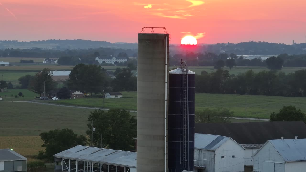 tramonto su terreni agricoli con silos e fienili