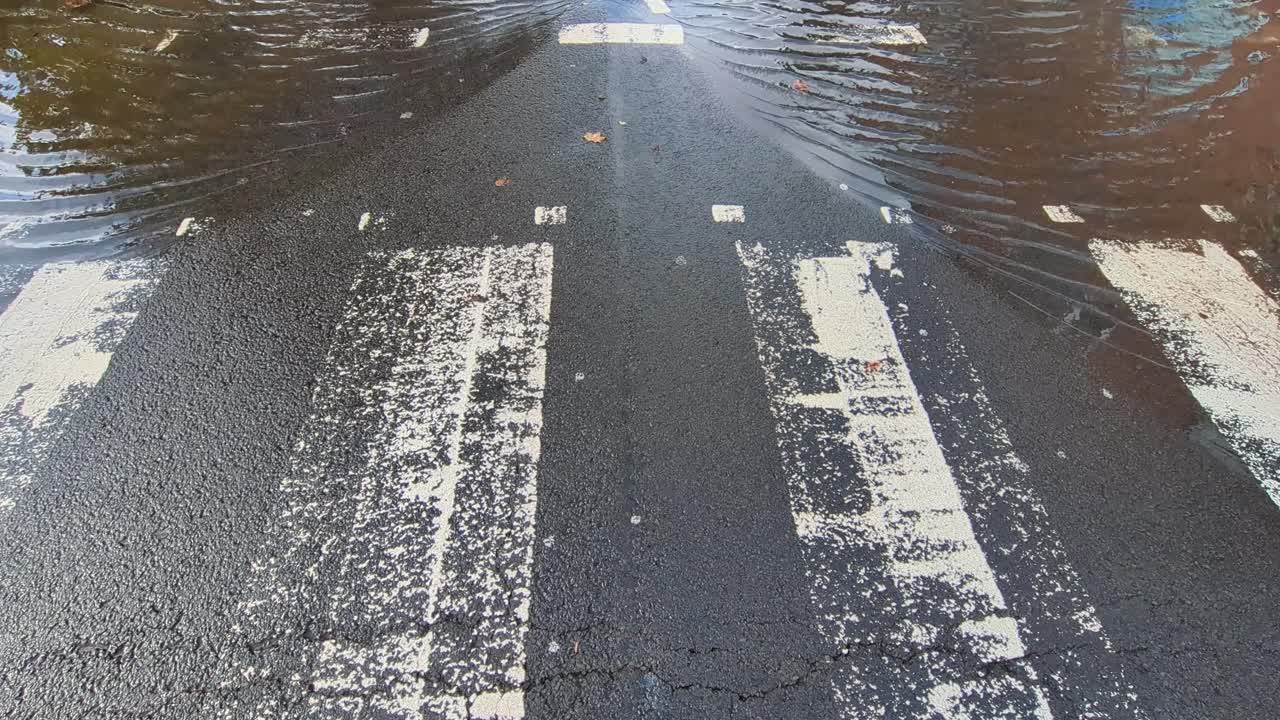Wide View of Flooded Shops and Business on Busy Road After Torrential Rainfall Flooded Roundabout. Filmed in Swansea, UK