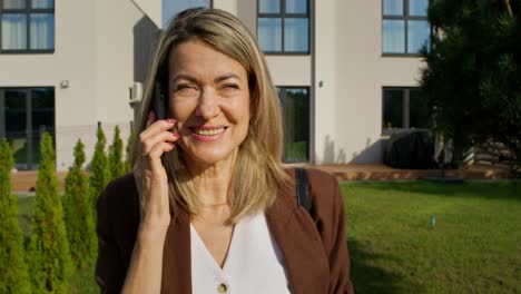 woman talking on phone in front of home