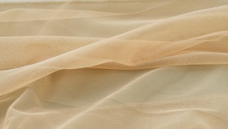 beige fine mesh close-up. sewing a wedding dress. light veil nylon. handmade tailoring, professional clothing concept. abstract background