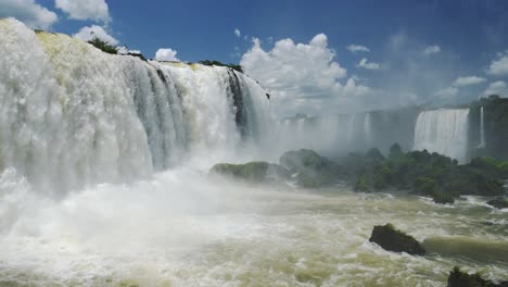 amazing nature scenery and long rough waterfalls falling on green coloured rocky floor in iguacu falls, brazil, south america, huge bright waterfall valley hidden in large green jungle