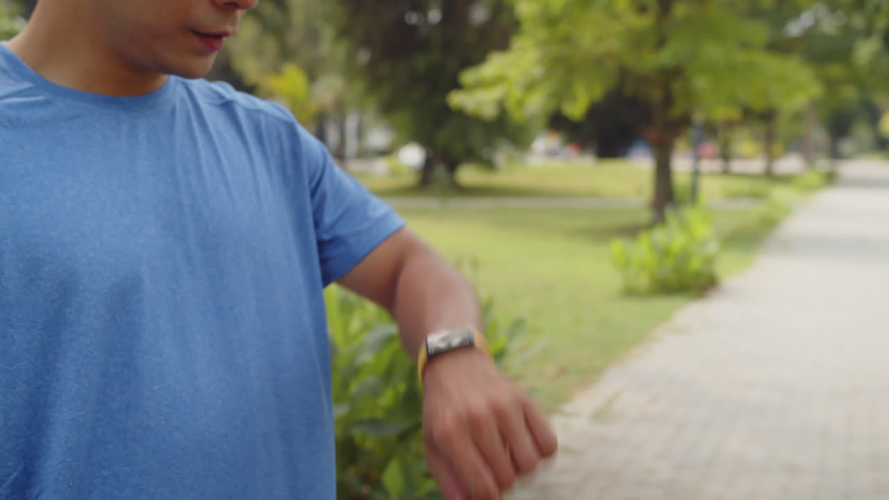 Sportivo che usa lo smartwatch durante l'allenamento mattutino nel parco