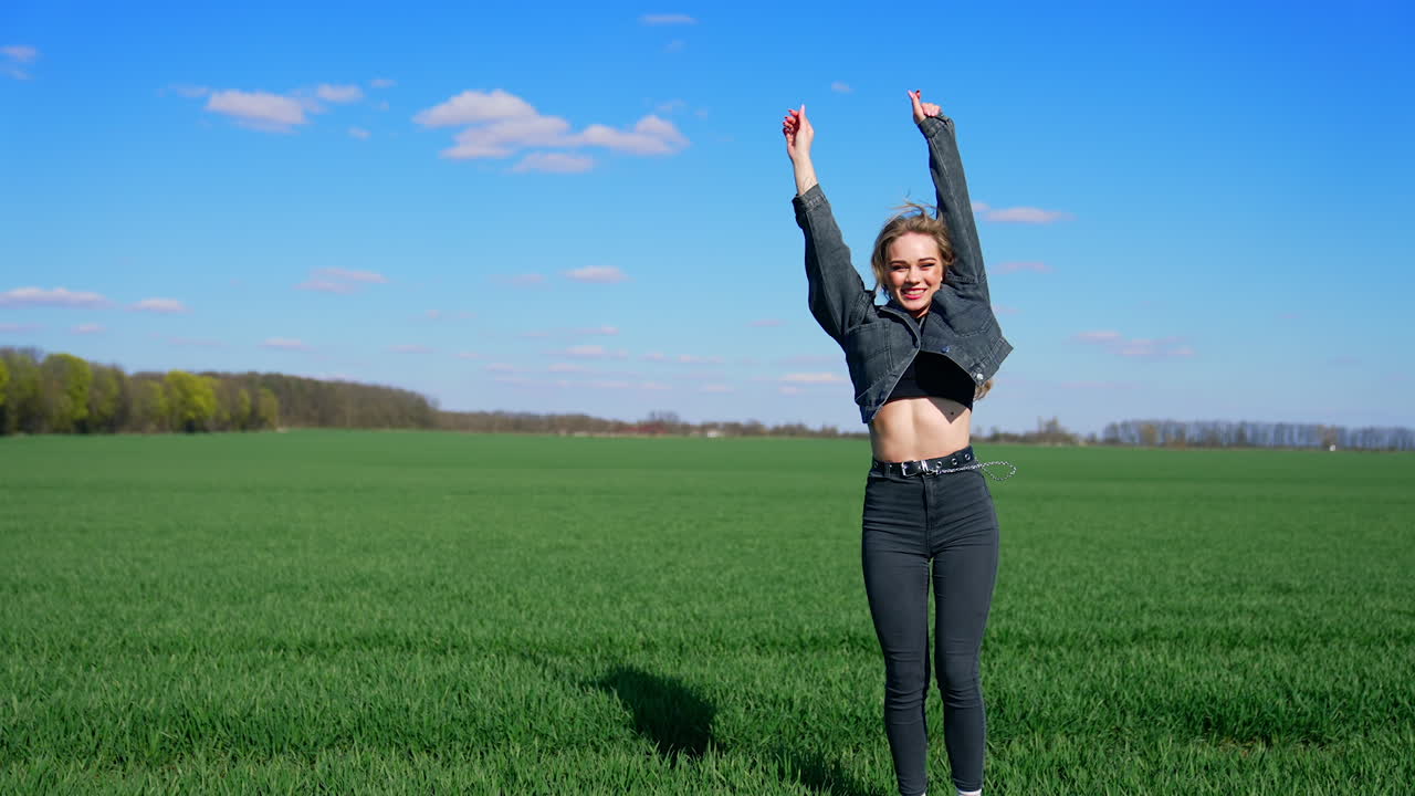 Happy young woman in spring day. Attractive girl in denim suit jumping happily on field in a bright day. Joyful girl on a green meadow.