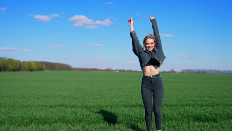 happy young woman in spring day. attractive girl in denim suit jumping happily on field in a bright day. joyful girl on a green meadow.