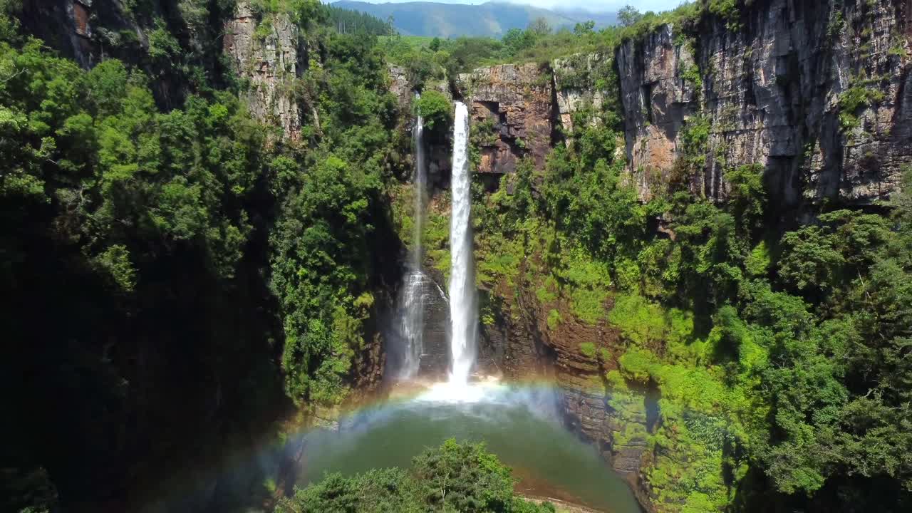 tiro de dron de la caída de mac mac en sudáfrica - dron está retrocediendo desde la cascada, mostrando un arco iris