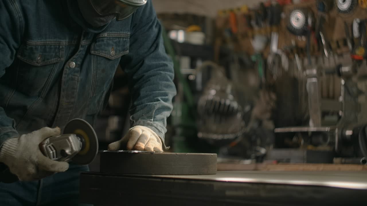 cerrajero en la seguridad máscara facial arena los bordes de un detalle metálico por molinillo eléctrico con muchas chispas en cámara lenta, metalurgia en el taller, 4k 60p prores hq