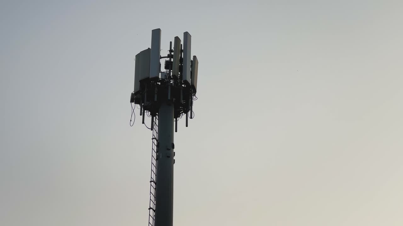 Closeup view of a monopole cell tower with antennas mounted near the top, showing a freestanding telecom structure forming part of a cell site for wireless communication