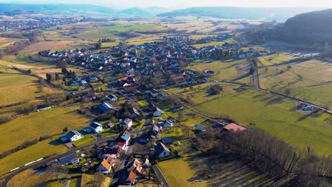 drone glides above quaint village nestled amongst gentle rolling hills