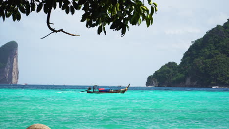 Tracking-shot-of-cruising-traditional-transport-boat-in-turquoise-clear-water-in-Thailand