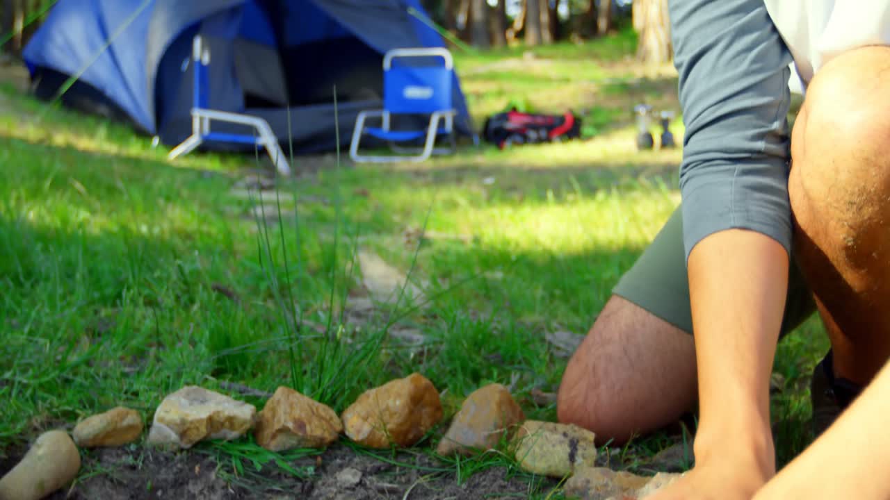 hombre preparando una hoguera en el bosque en un día soleado 4k