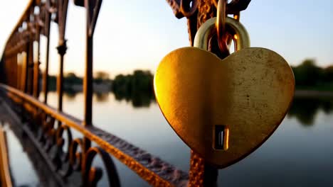 heart-shaped lock on a bridge at sunset