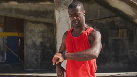 african american man checking his smartwatch, taking break in exercise outdoors