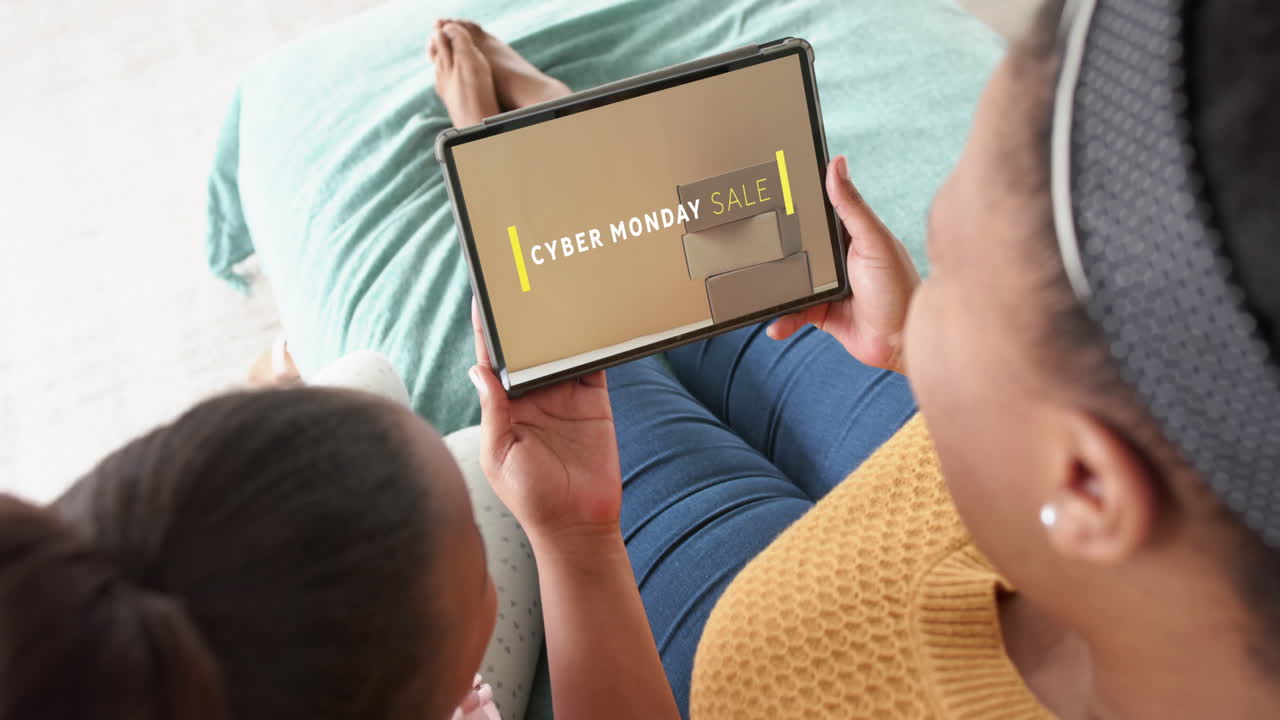African american mother and daughter using tablet, shopping online on cyber monday, slow motion