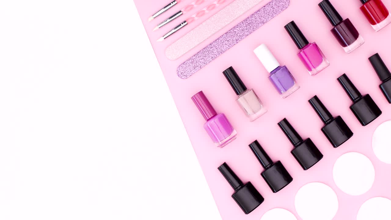 Nail gel polishes and manicure tools appear on pink white theme. Stop motion