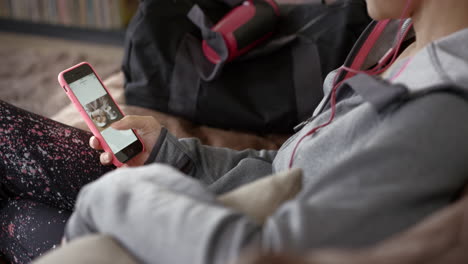 Mujer-Deportiva-Escuchando-Música-Navegando-Por-Internet-En-Un-Teléfono-Inteligente-En-Casa-Relajándose-En-El-Sofá