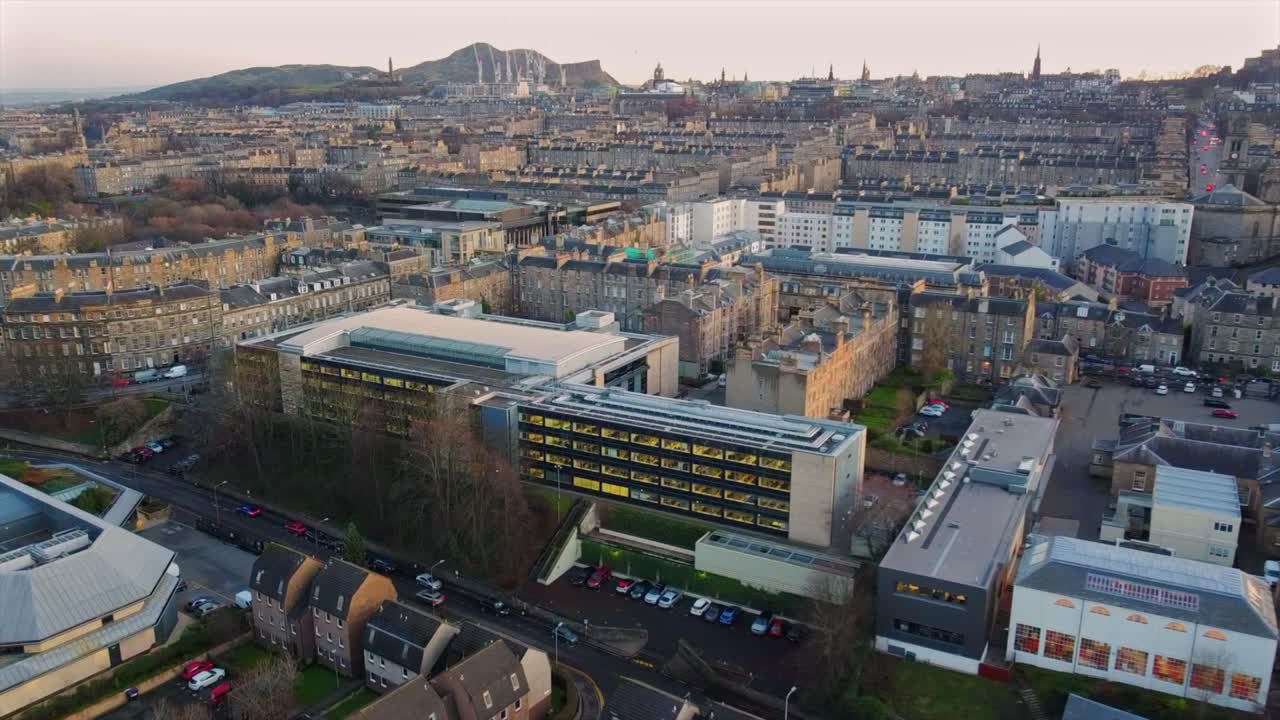 Drone footage capturing a blend of modern office buildings and traditional Edinburgh residential architecture. Arthur’s Seat is visible in the background, showcasing the city’s iconic skyline.