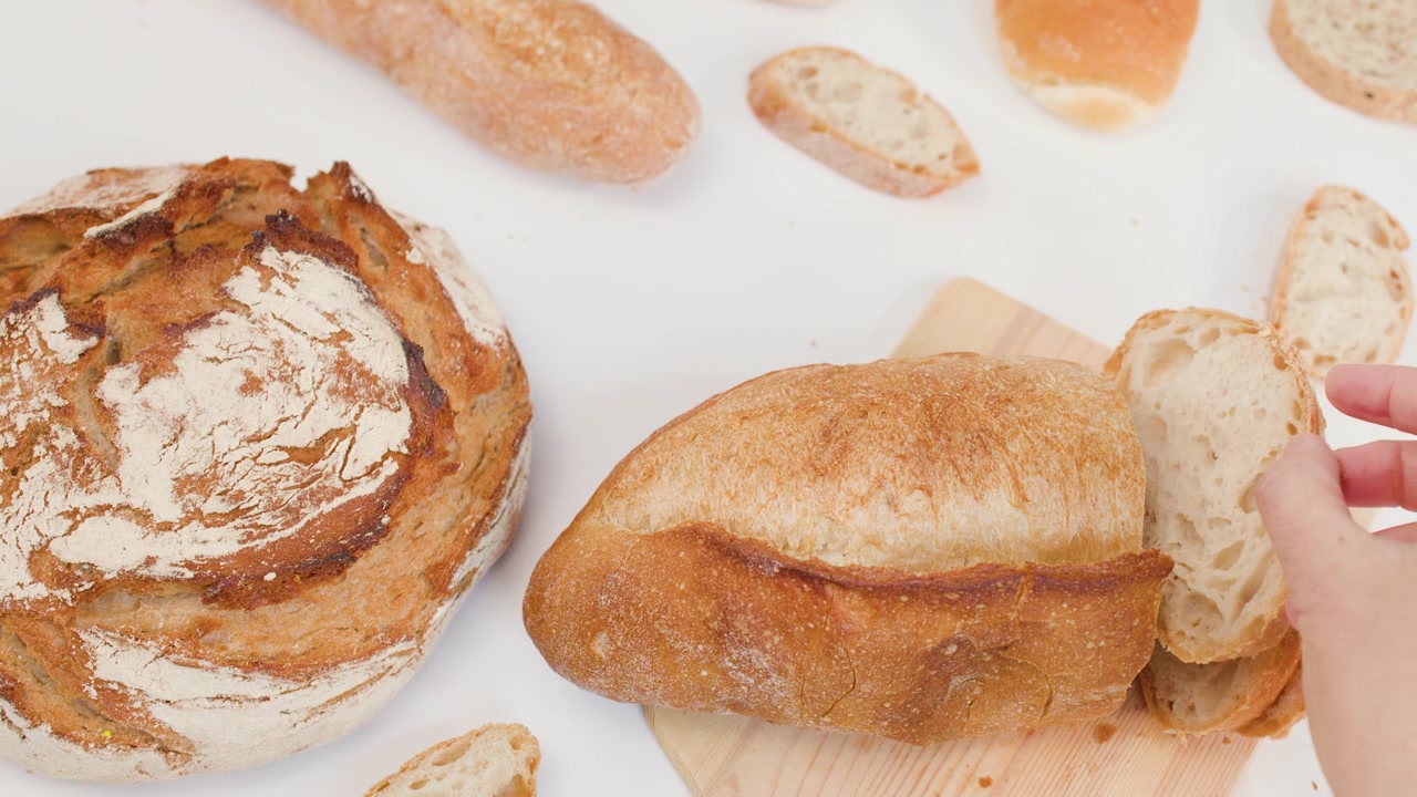 Persona che affetta pane fresco e croccante su un tagliere di legno