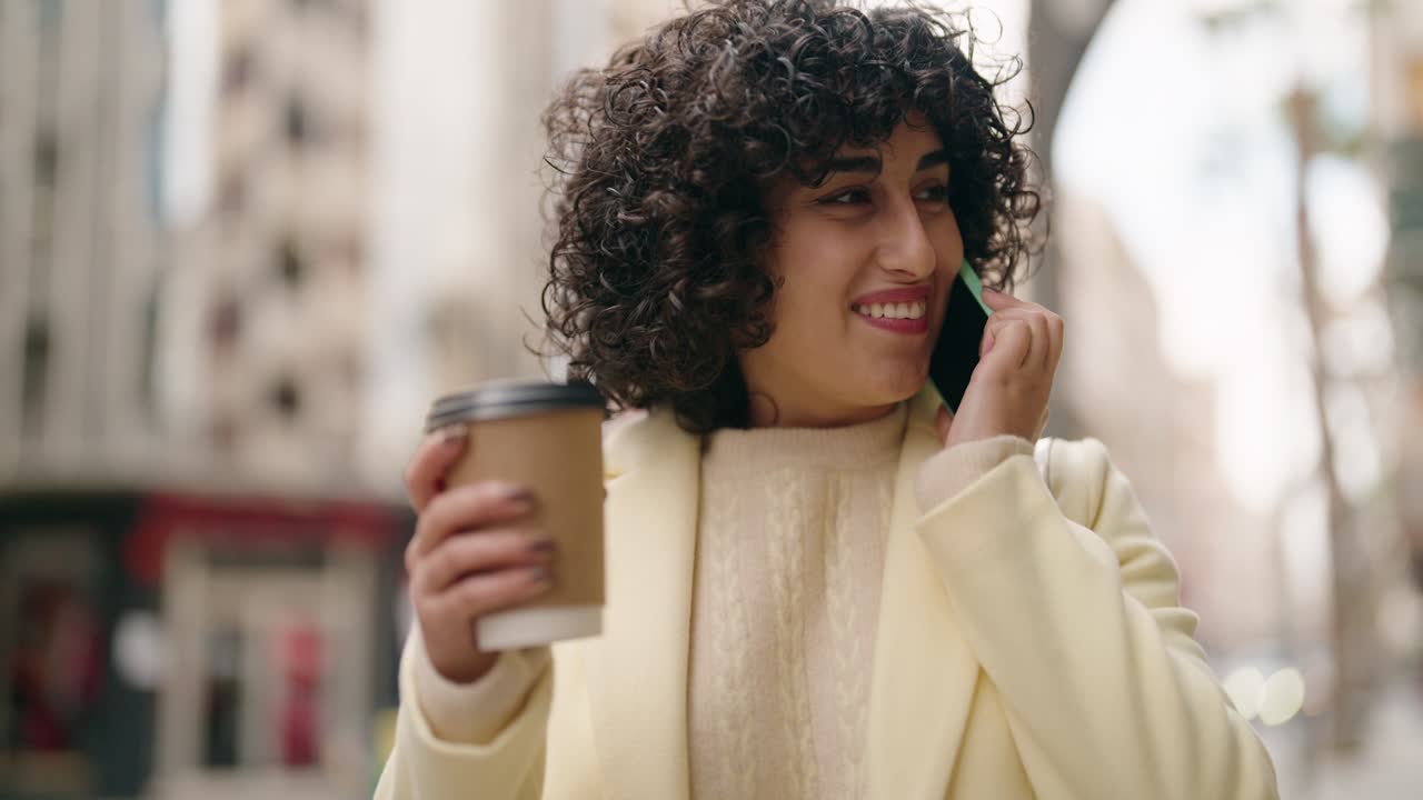 joven hablando en el teléfono inteligente bebiendo café en la calle