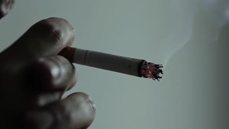 a close-up exploration of smoking: the final moments of a cigarette as it wanes and glows, capturing the intimate interaction with a hand and a lighter flame