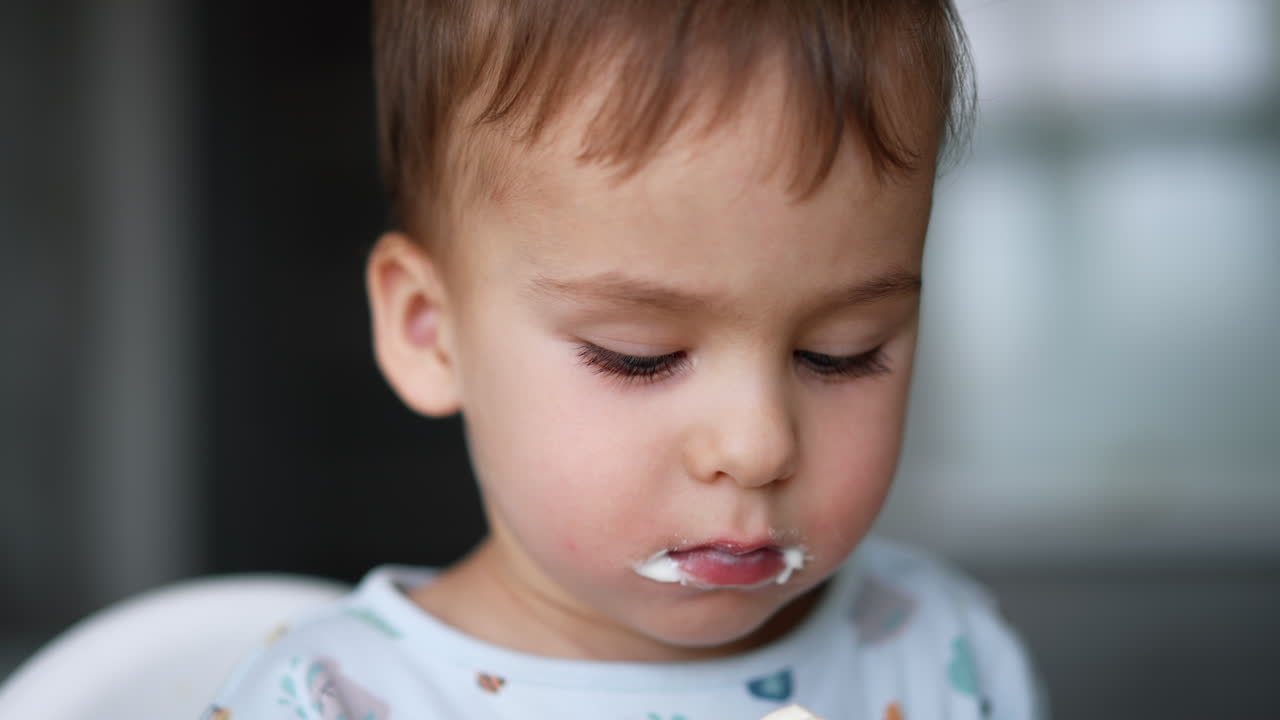Charming Caucasian baby boy eating yogurt. Close up portrait of a toddler having healthy meals.