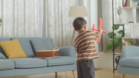 asian kid playing toy plane at home