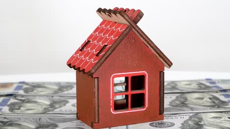 model of small familly house standing on background of dollars banknotes and rotate slowly.