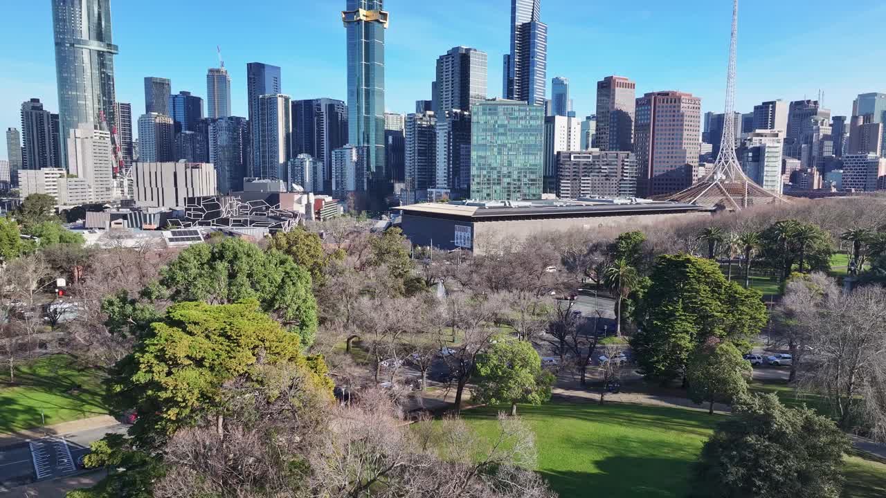 Aerial rise up from Queen Victoria Gardens to show Melbourne Arts Centre and CBD