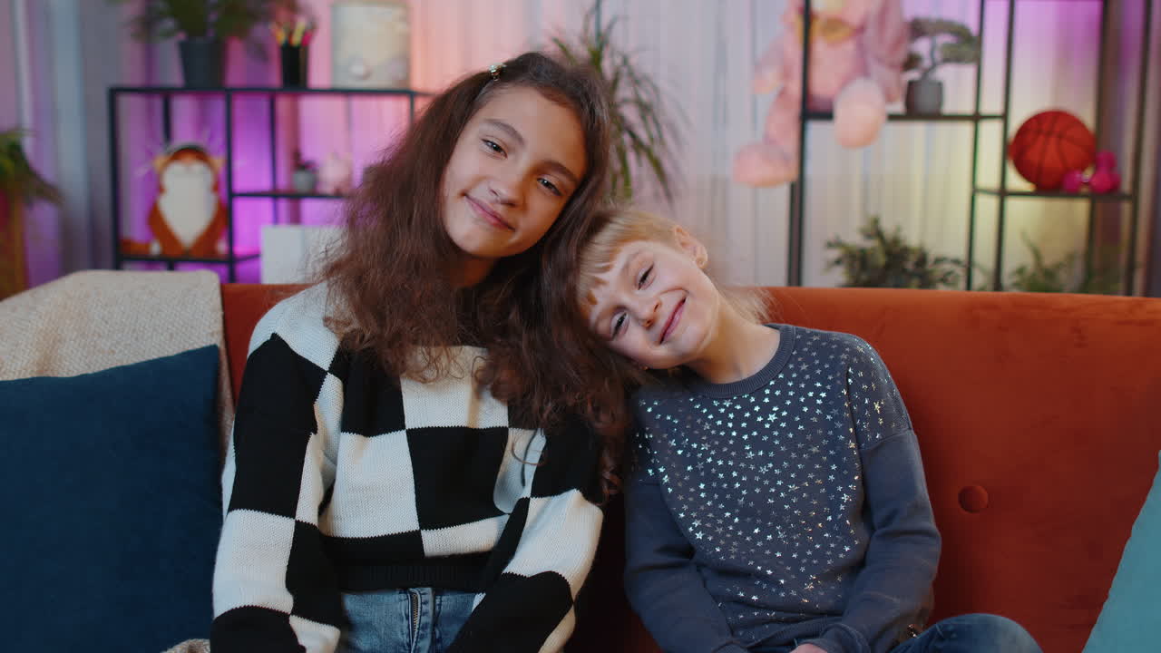 Portrait of happy smiling teenage child and little sister kid looking at camera at home play room