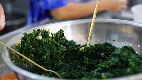 hands mixing and squeezing spinach in a bowl