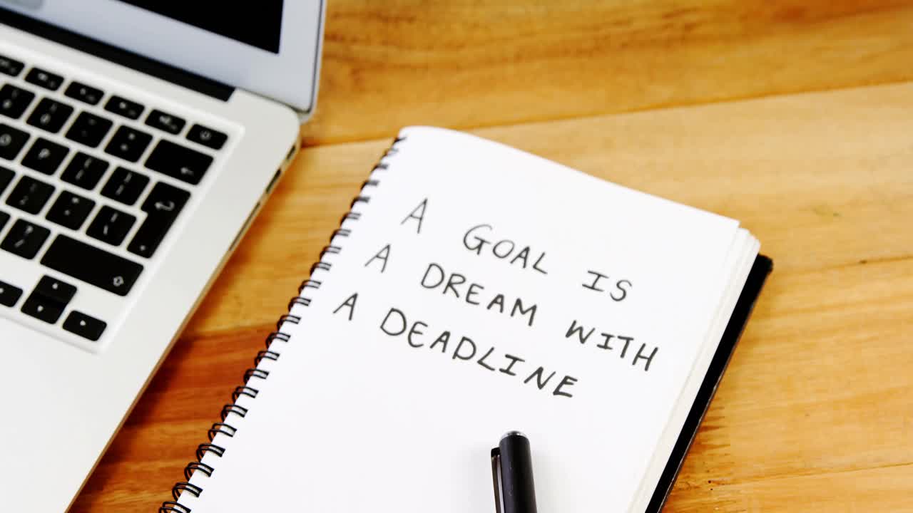Text written on diary with laptop on table