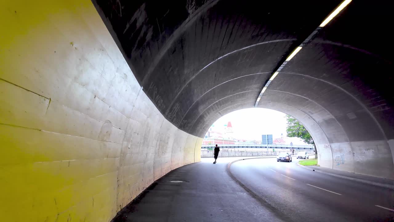 Passau walking through tunnel with yellow wall, with skater and cars and revealing Danube river with cruise ship and row of houses, Germany