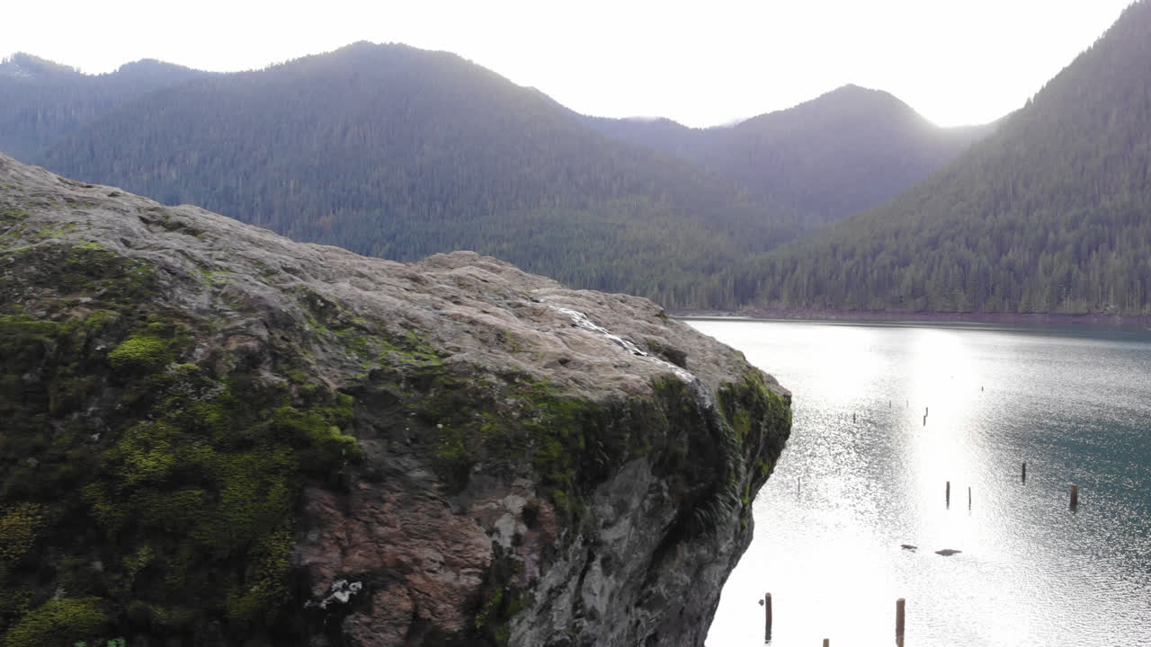 아름다운 푸른 호수 근처의 이끼 바위 주위를 날아다니는 드론