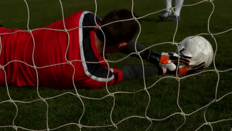 goalkeeper in red letting in a goal during a game