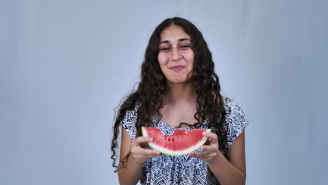 feliz adolescente con el pelo largo y rizado comiendo sandía, fondo blanco
