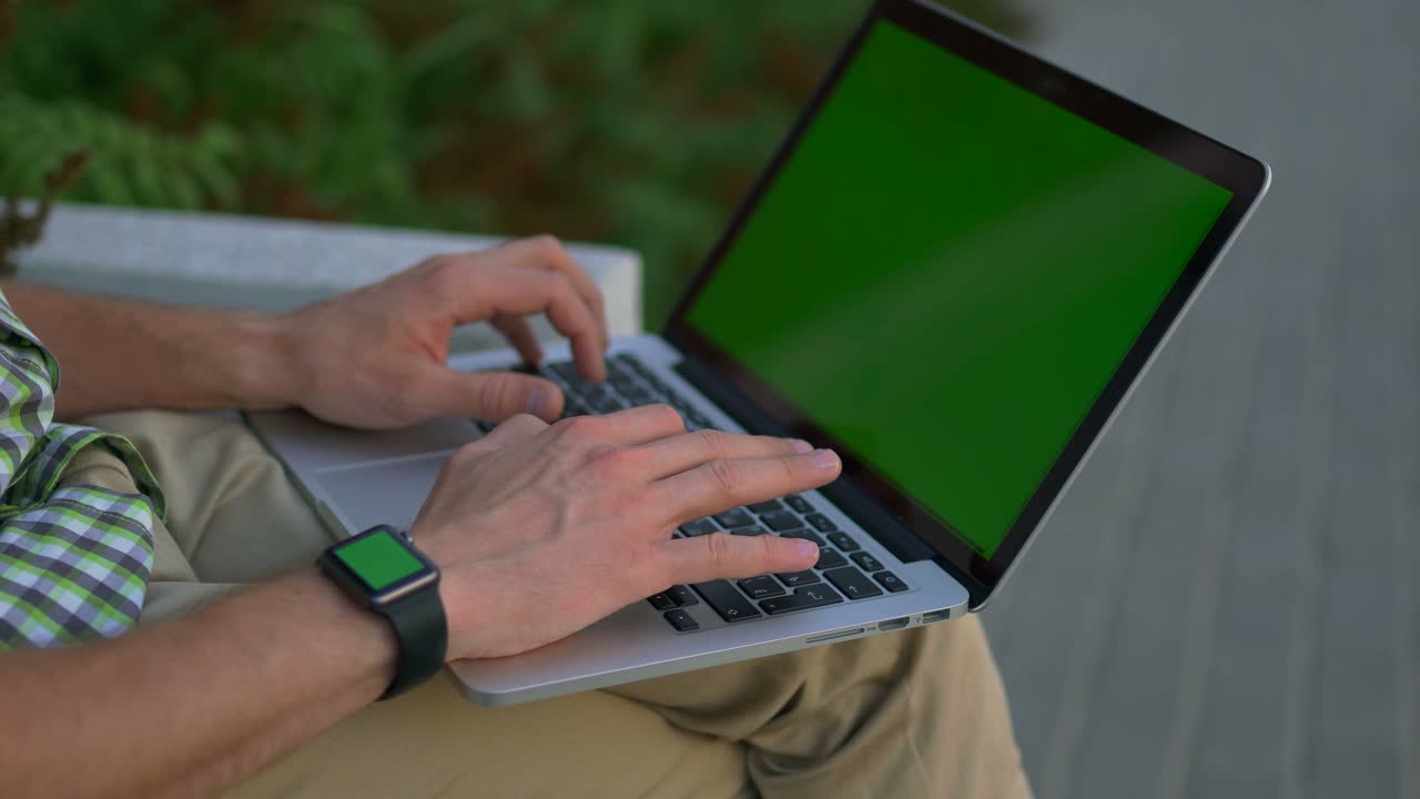 persona que utiliza una computadora portátil y un reloj inteligente al aire libre