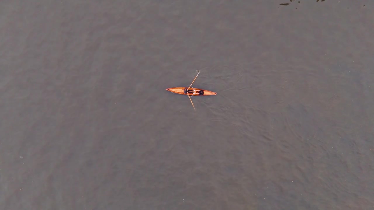 Rower paddling single scull on calm river, aerial view shows solo recreation