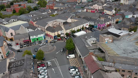 Tiro-Circular-Del-Centro-De-La-Ciudad.-Plaza-Con-Rotonda-Y-Coches-Aparcados.-Calles-Comerciales-Alrededor.-Ennis,-Irlanda