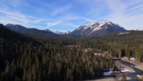 majestic scenic shot of snow capped mountain range, river and evergreen forest in cle elum on a blue sky day in washington state