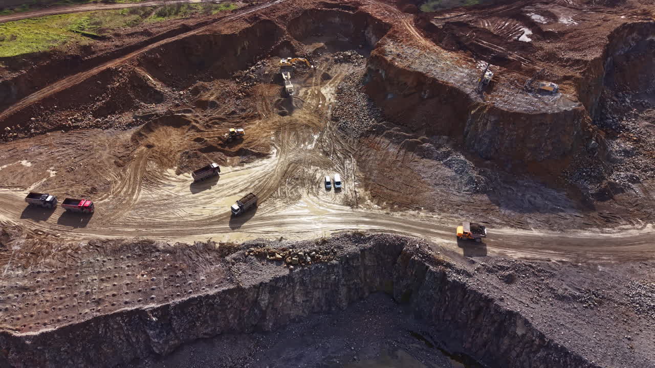Granite quarry operation showing machinery and workers in large mining area at midday