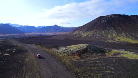 Car-driving-through-dirty-road-between-volcanoes-in-Iceland-at-daytime