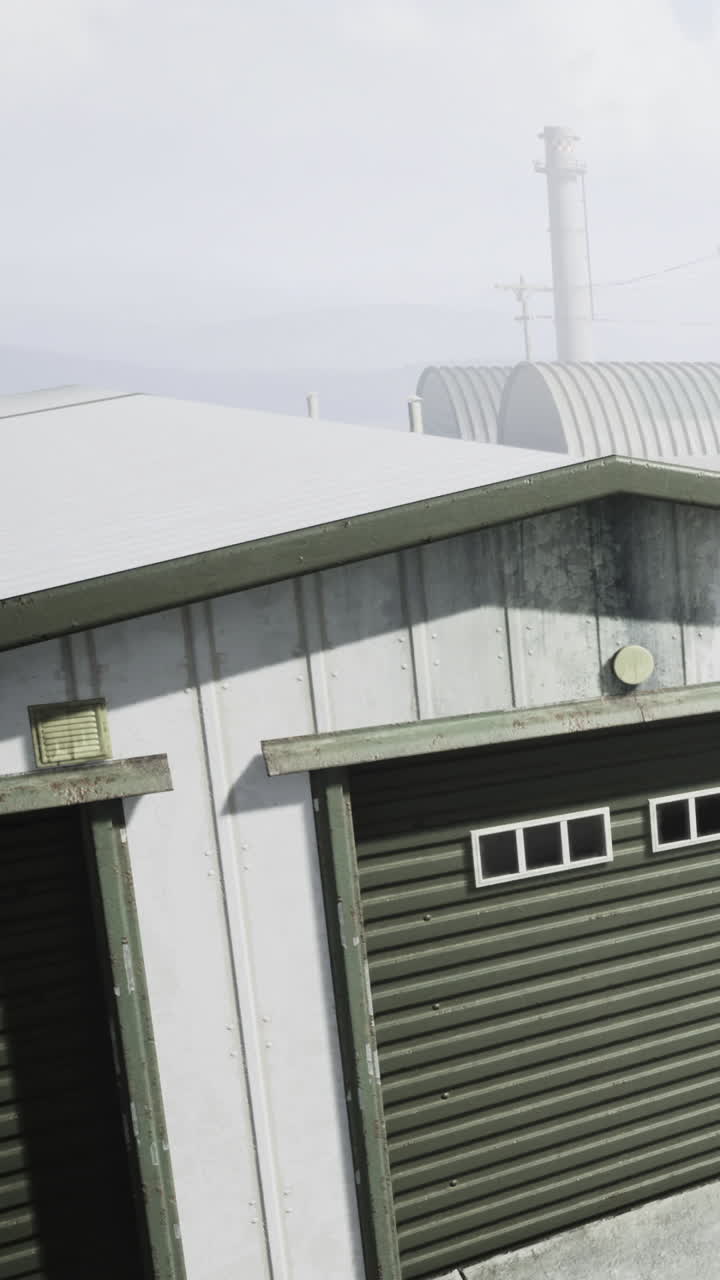 Edificio con porte verdi vicino a una zona industriale in una giornata nuvolosa.
