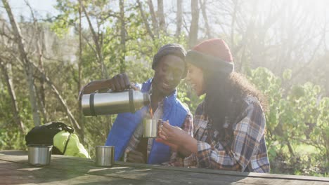 Smiling-diverse-couple-drinking-tea-and-hiking-in-countryside