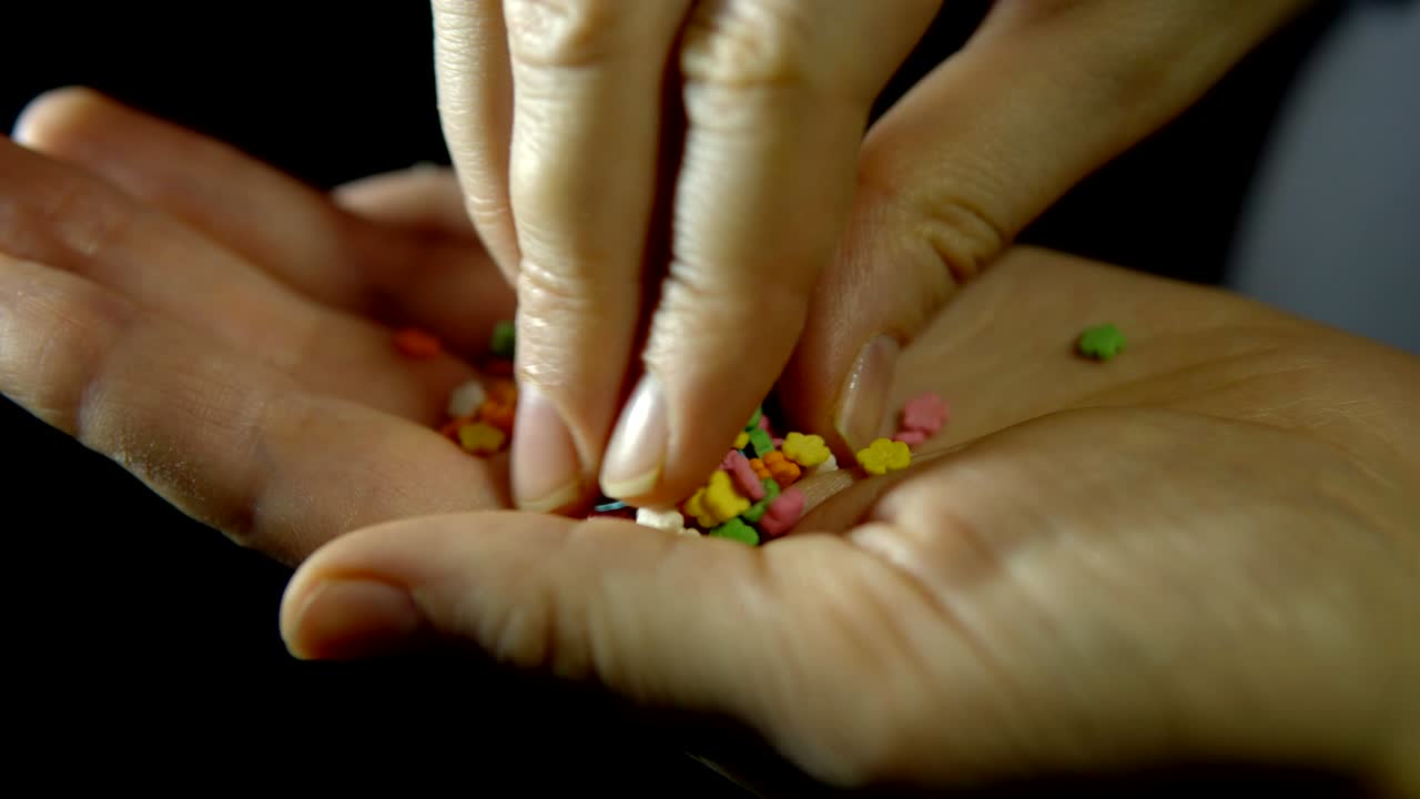 검은색 바탕에 있는 사람의 손에 있는 은 과자 가루입니다.