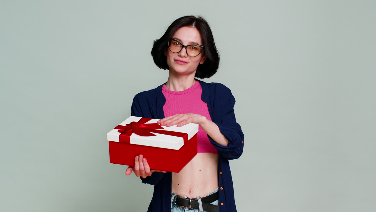 Woman mysteriously smiling extending hands forward holding gift box expressing surprise present