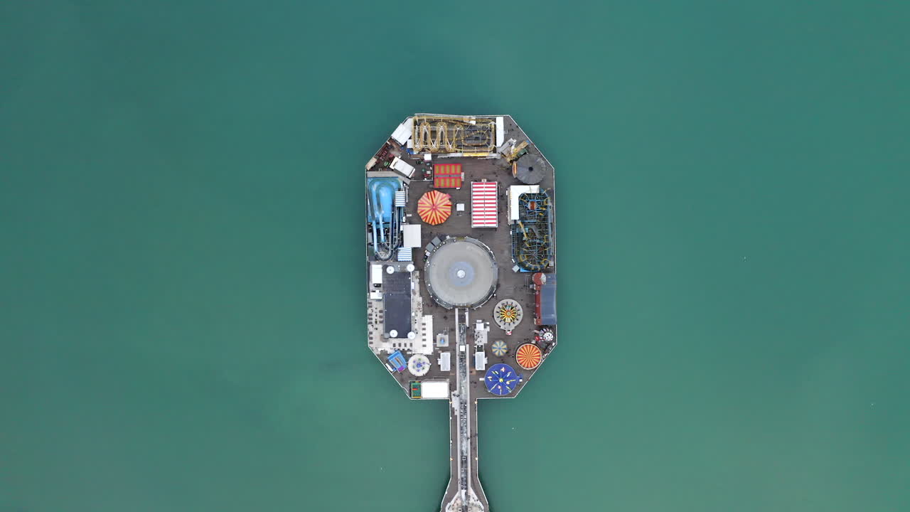 A top-down aerial shot of Palace pier in Brighton with fairground rides located on the South coast of England with amusement rides in action