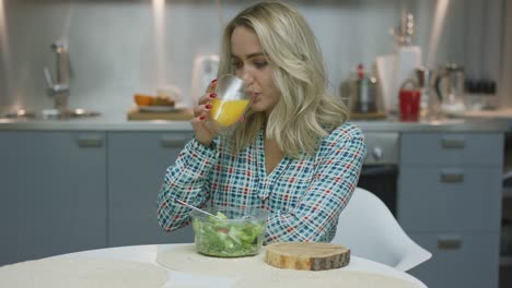 mujer bebiendo jugo y comiendo ensalada