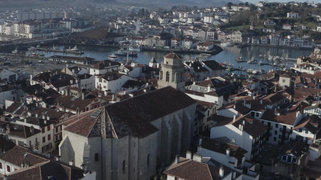 Saint-Jean-Baptiste church, bell tower, Saint-Jean-de-Luz historic centre, cityscape, port, France. Aerial orbiting