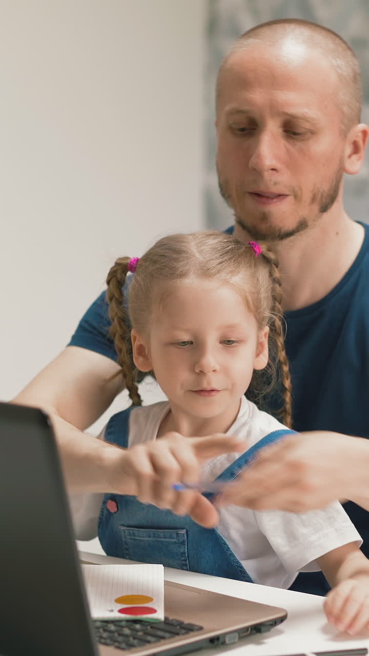 young dad and little daughter student sits on his knees, hastily quickly preparing for online learning, girl and father take up pens as fast, notebooks, listen to teacher